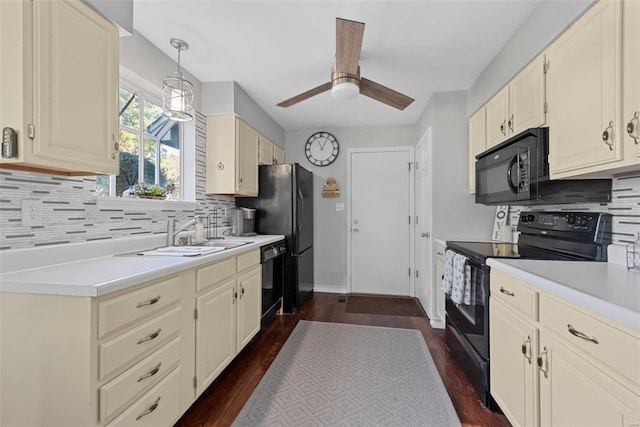 kitchen with decorative light fixtures, black appliances, sink, and dark hardwood / wood-style flooring