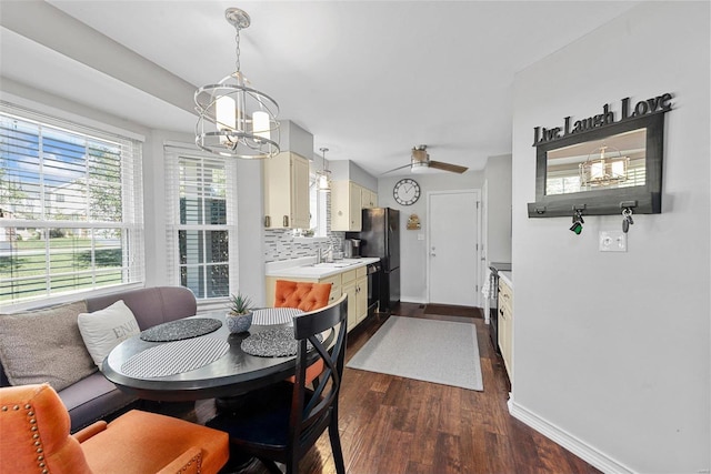 dining space with sink, dark wood-type flooring, and ceiling fan with notable chandelier