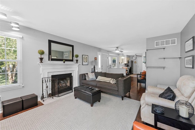 living room featuring a tiled fireplace, wood-type flooring, and ceiling fan