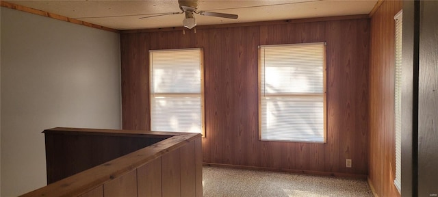 interior space with wood walls, ceiling fan, and light colored carpet