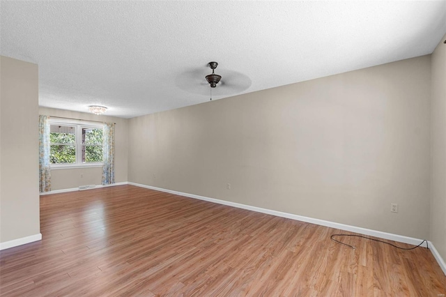 empty room with ceiling fan, a textured ceiling, and light hardwood / wood-style flooring