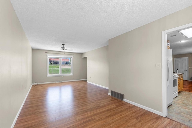 unfurnished room featuring light hardwood / wood-style floors, ceiling fan, and a textured ceiling