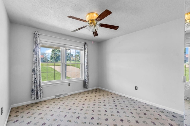 carpeted empty room with ceiling fan and a textured ceiling