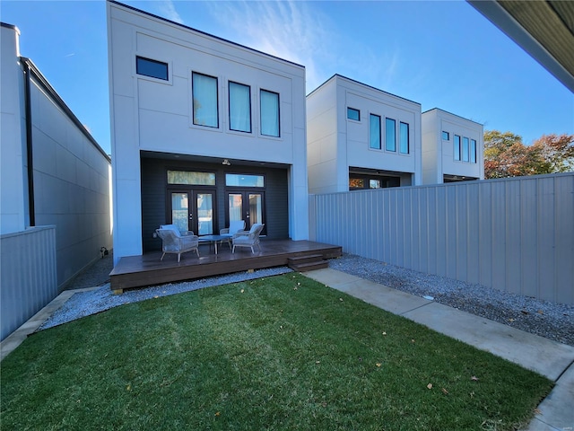 back of property featuring a deck, a yard, and french doors