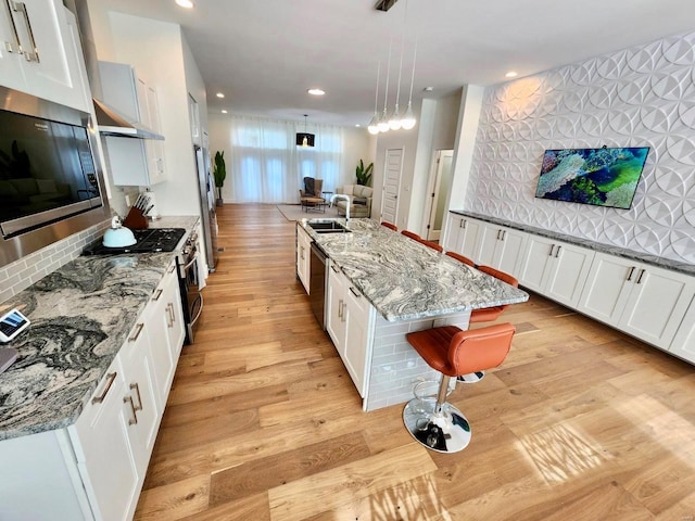 kitchen with light hardwood / wood-style flooring, white cabinets, and hanging light fixtures