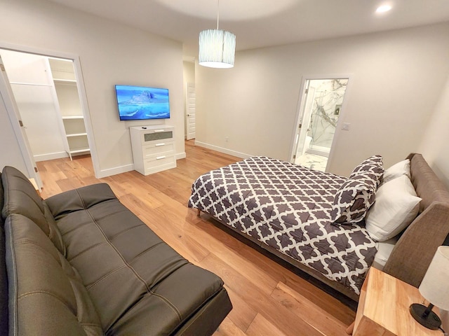 bedroom with light wood-type flooring and a walk in closet