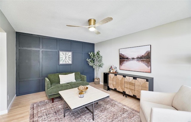 living room with ceiling fan, light hardwood / wood-style floors, and a textured ceiling