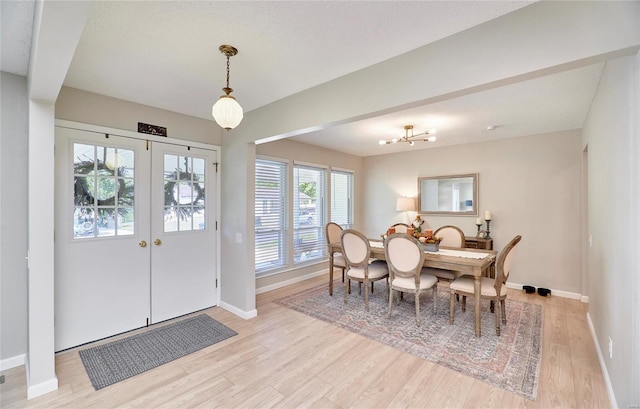 dining room with an inviting chandelier, a textured ceiling, and light wood-type flooring