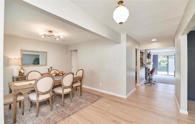 dining area featuring a textured ceiling, light hardwood / wood-style flooring, and a notable chandelier