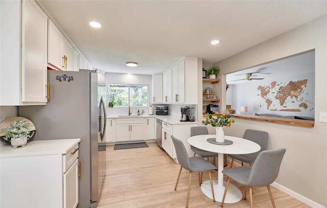 kitchen with appliances with stainless steel finishes, ceiling fan, sink, light hardwood / wood-style floors, and white cabinetry