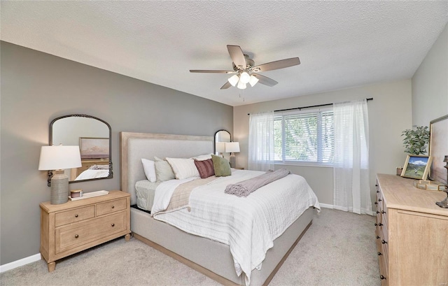 bedroom featuring ceiling fan, light colored carpet, and a textured ceiling