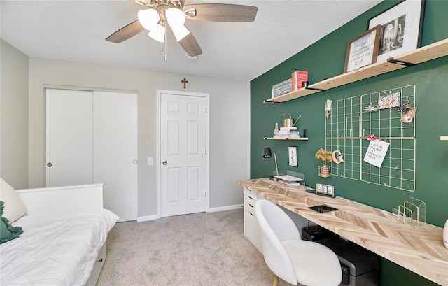 home office featuring ceiling fan, light colored carpet, and a textured ceiling