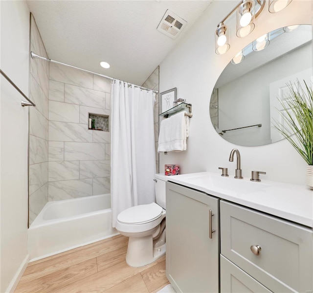 full bathroom with shower / bath combo, vanity, a textured ceiling, hardwood / wood-style flooring, and toilet