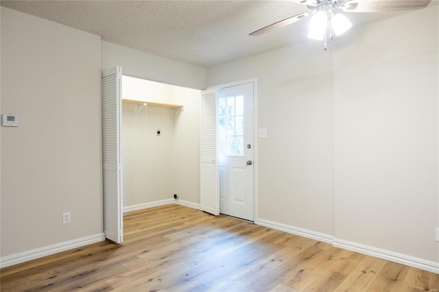 interior space featuring light wood-type flooring, a textured ceiling, electric dryer hookup, and ceiling fan