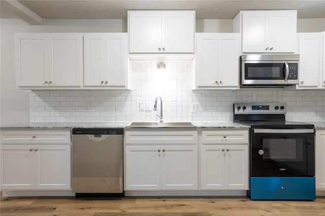 kitchen featuring sink, white cabinetry, light hardwood / wood-style flooring, stainless steel appliances, and backsplash