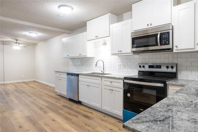 kitchen featuring stainless steel appliances, white cabinetry, light wood-type flooring, and sink