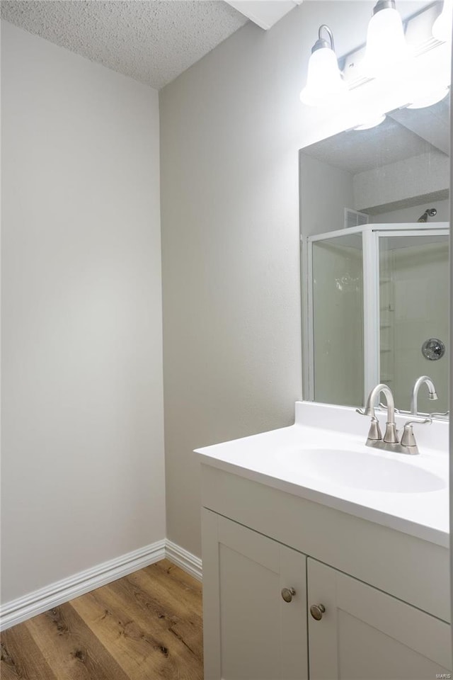 bathroom featuring a shower with door, hardwood / wood-style flooring, vanity, and a textured ceiling