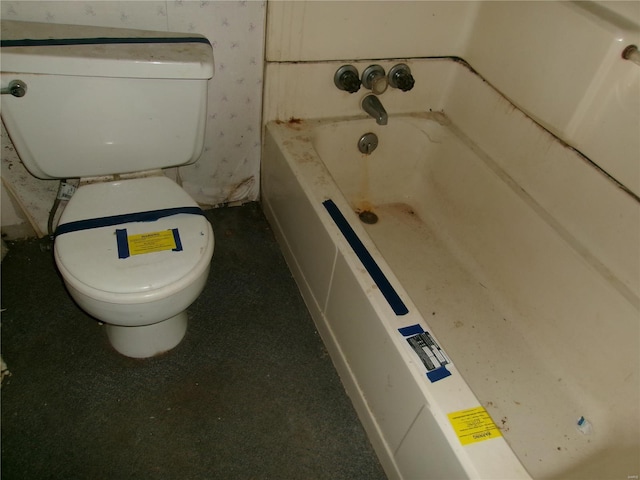 bathroom with a tub to relax in and toilet