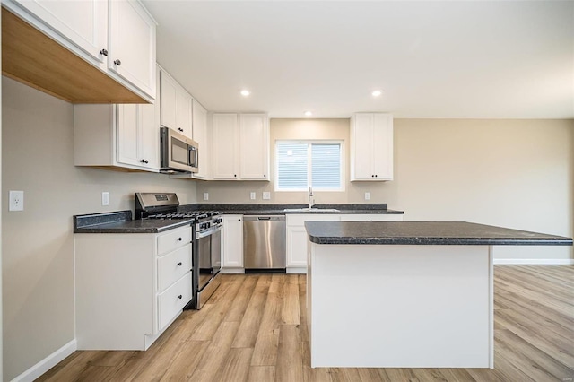 kitchen with sink, white cabinetry, stainless steel appliances, light hardwood / wood-style floors, and a kitchen island