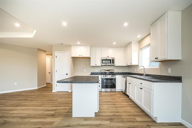 kitchen with white cabinetry, stainless steel appliances, sink, and a kitchen island