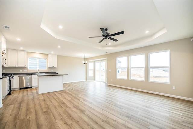 kitchen with white cabinets, hanging light fixtures, light hardwood / wood-style floors, a tray ceiling, and stainless steel appliances