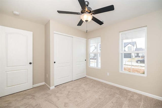 unfurnished bedroom featuring light colored carpet, a closet, and ceiling fan