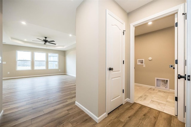 hall featuring a tray ceiling and light wood-type flooring