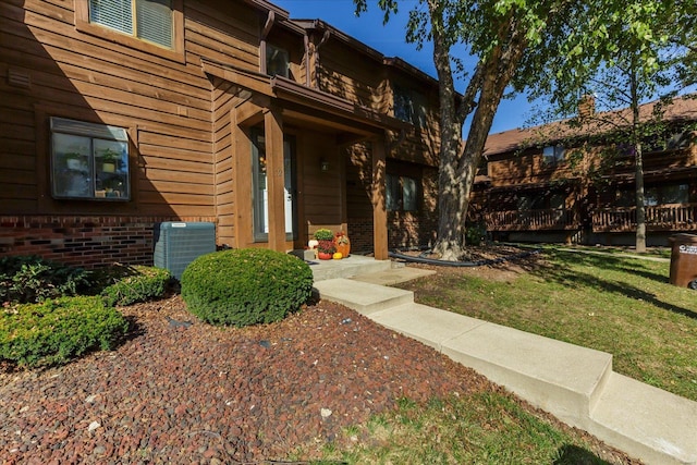 property entrance featuring a yard, central air condition unit, and a wooden deck