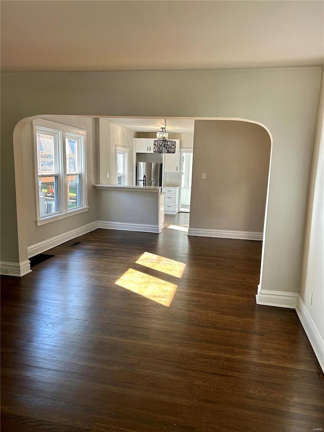 unfurnished living room featuring a chandelier and dark hardwood / wood-style flooring