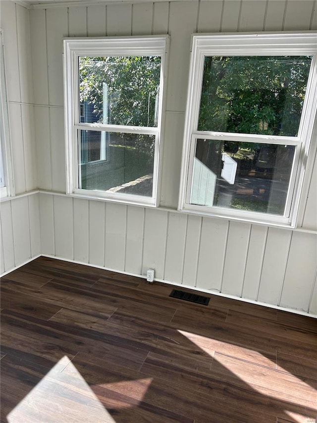 empty room featuring wood walls and dark wood-type flooring