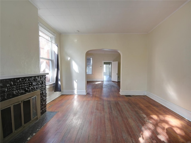 unfurnished living room featuring crown molding, a stone fireplace, and dark hardwood / wood-style flooring