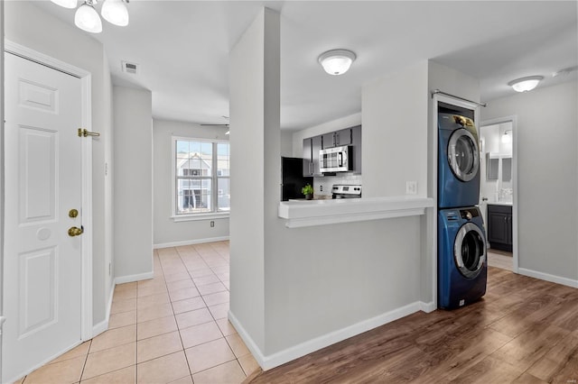 interior space featuring ceiling fan, stacked washer and clothes dryer, and light wood-type flooring