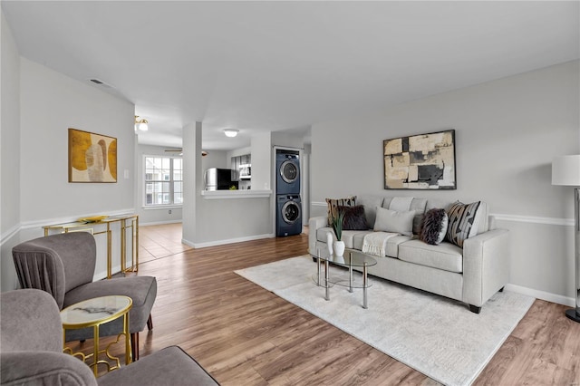 living room with light hardwood / wood-style flooring and stacked washer and clothes dryer