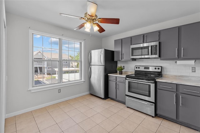 kitchen with decorative backsplash, stainless steel appliances, gray cabinetry, and light tile patterned flooring