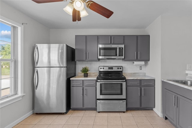 kitchen featuring stainless steel appliances, backsplash, and gray cabinetry