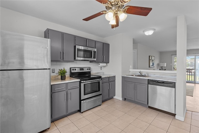 kitchen with ceiling fan, sink, gray cabinets, appliances with stainless steel finishes, and decorative backsplash