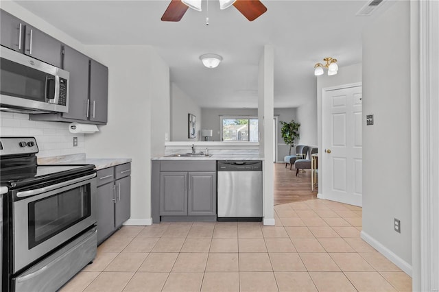 kitchen with backsplash, appliances with stainless steel finishes, light tile patterned flooring, and sink