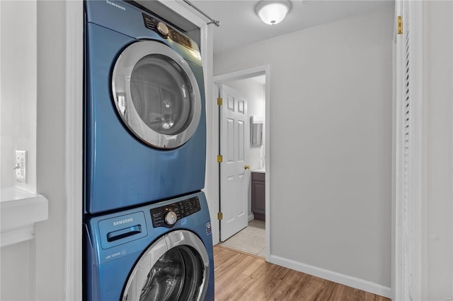 clothes washing area with light hardwood / wood-style flooring and stacked washer / dryer