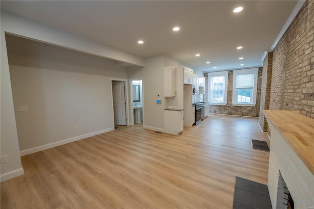 unfurnished living room featuring brick wall, light wood-type flooring, and sink