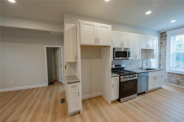 kitchen with white cabinets, light hardwood / wood-style floors, appliances with stainless steel finishes, and sink