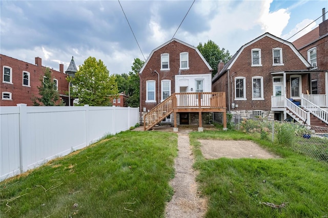 back of property featuring a wooden deck and a lawn