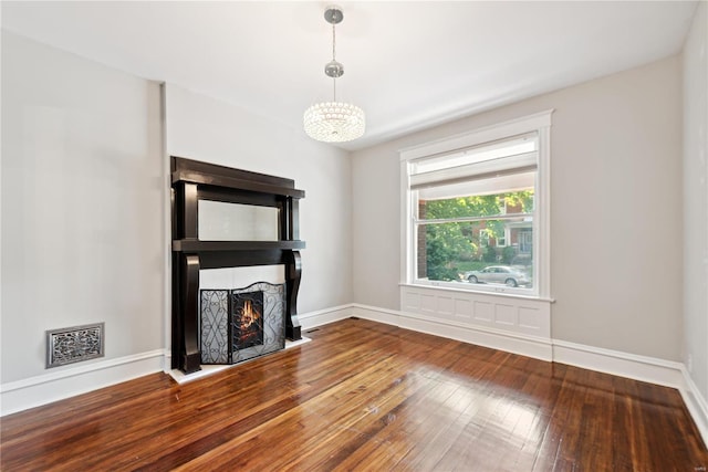 unfurnished living room with hardwood / wood-style floors and an inviting chandelier