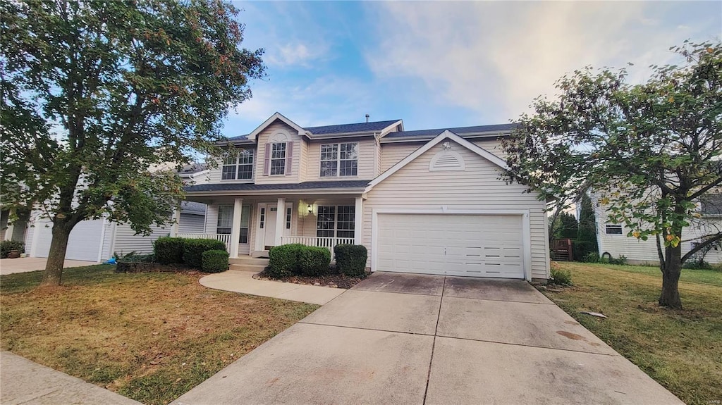 view of front of property featuring a front yard, a garage, and covered porch