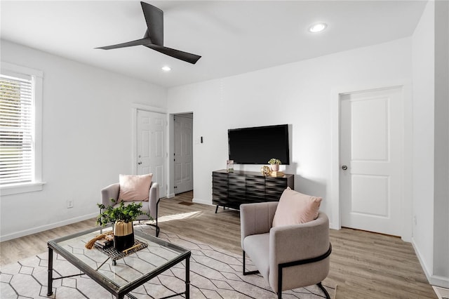 living room with light hardwood / wood-style flooring and ceiling fan