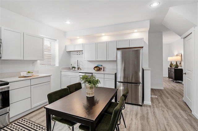 kitchen with white cabinetry, light hardwood / wood-style floors, appliances with stainless steel finishes, and sink