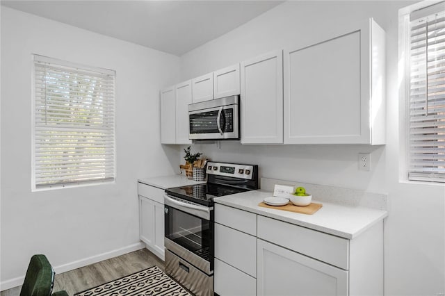 kitchen with light hardwood / wood-style flooring, stainless steel appliances, and white cabinets