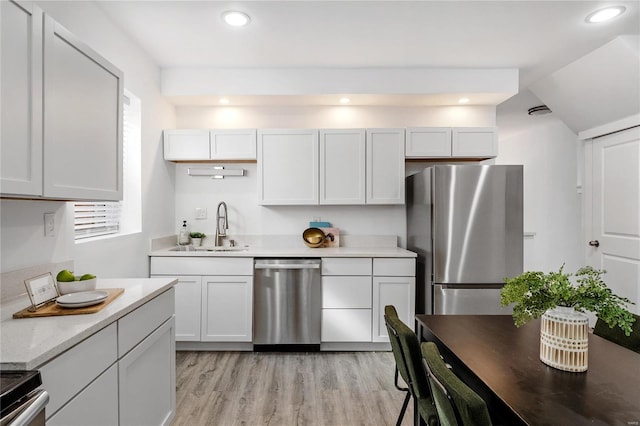 kitchen with white cabinets, appliances with stainless steel finishes, light wood-type flooring, and sink