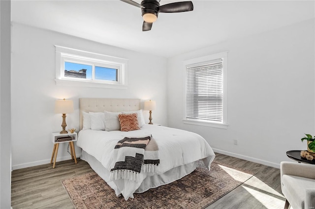 bedroom featuring ceiling fan, light hardwood / wood-style flooring, and multiple windows