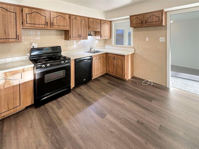 kitchen with decorative backsplash, black appliances, dark wood-type flooring, and sink