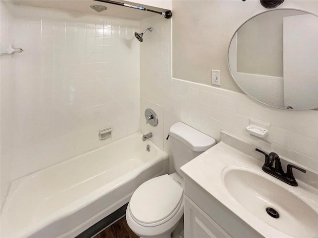 full bathroom with tiled shower / bath combo, tile walls, toilet, and vanity